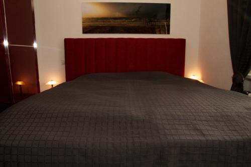 Schlafzimmer mit einem Bett mit rotem Kopfteil in der Unterkunft Tag am Meer Sylt in Westerland