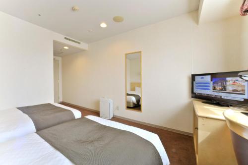 a bedroom with two beds and a flat screen tv at Yamagata Kokusai Hotel in Yamagata