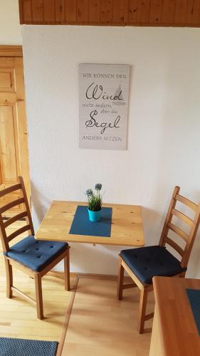 a wooden table with two chairs and a potted plant on it at Ankerplatz, Am Hafen Ost 10 in Carolinensiel