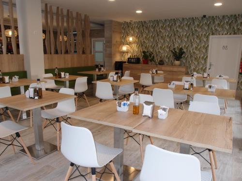 a restaurant with wooden tables and white chairs at Hospedium Hotel Abril in San Juan de Alicante