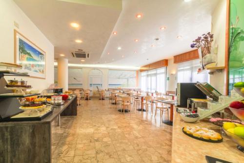 a restaurant with a buffet line with tables and chairs at Hotel Airone in Bibione