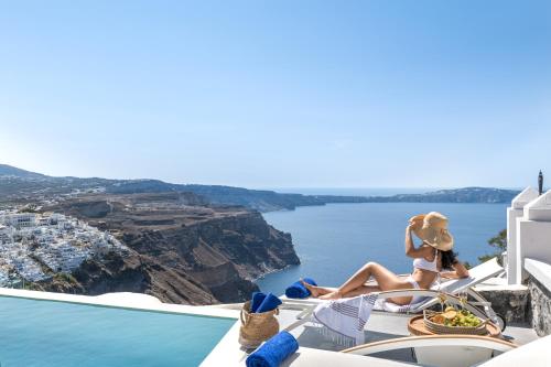 a woman sitting on a chair looking out over the ocean at Mythical Blue Luxury Suites in Fira