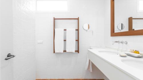 a white bathroom with a sink and a mirror at Real Agua Amarga La Joya - Adults Only in Agua Amarga