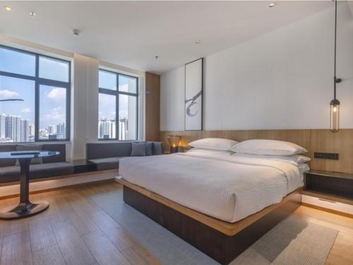 a bedroom with a bed and a desk and windows at GreenTree Eastern Binhu Road Wanda Hotel in Nanning