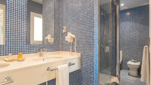 W wyłożonej niebieskimi kafelkami łazience znajduje się umywalka i prysznic. w obiekcie Real Agua Amarga La Joya - Adults Only w mieście Agua Amarga