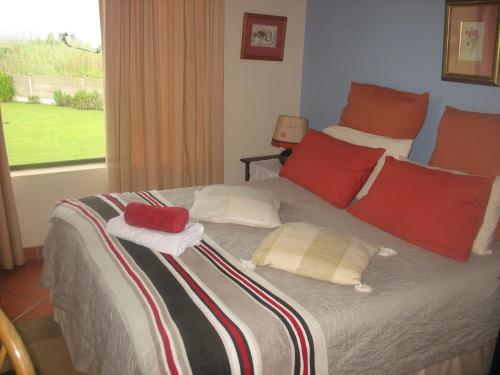 Bottlenose B&B في بورت إدوارد: غرفة نوم بسرير ومخدات حمراء ونافذة