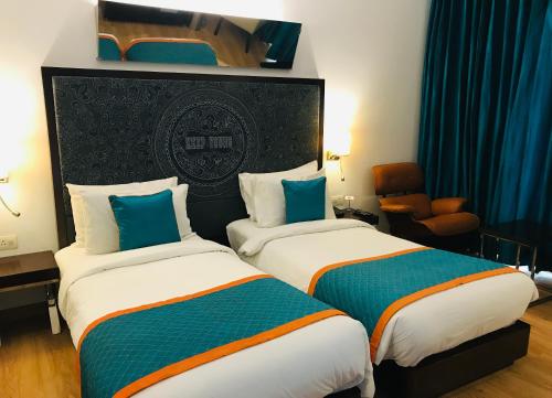 a hotel room with two beds and a chair at Golden Tulip City Centre Gurgaon in Gurgaon