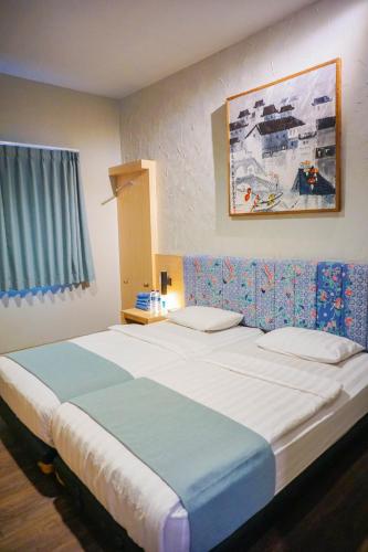a bedroom with a large bed with a painting on the wall at Hotel Pantes Semawis Pecinan SMG - Petfriendly Hotel in Semarang