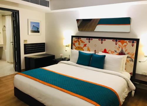 a bedroom with a large bed with blue pillows at Golden Tulip City Centre Gurgaon in Gurgaon