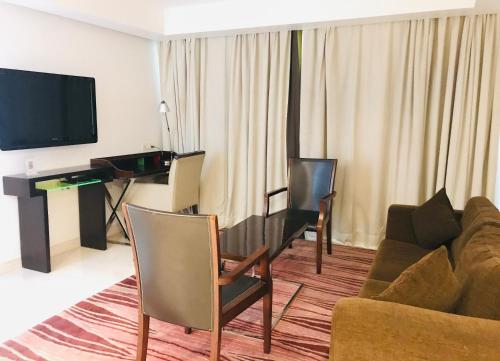 a living room with a couch and a desk with a television at Golden Tulip City Centre Gurgaon in Gurgaon