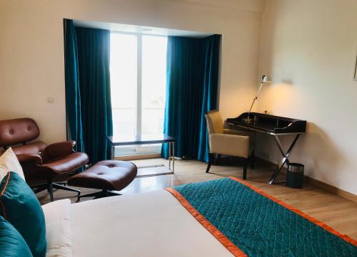 a bedroom with a bed and a desk and a piano at Golden Tulip City Centre Gurgaon in Gurgaon
