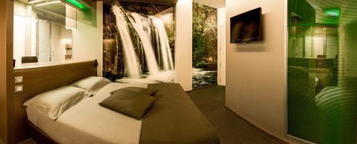 a bedroom with a bed and a waterfall painting on the wall at Pineta Hotel in Monsano