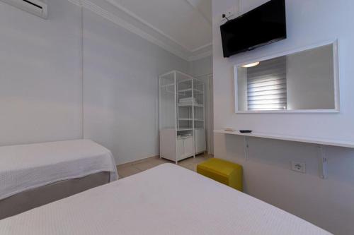 a white room with two beds and a television at Hola Bodrum in Mugla