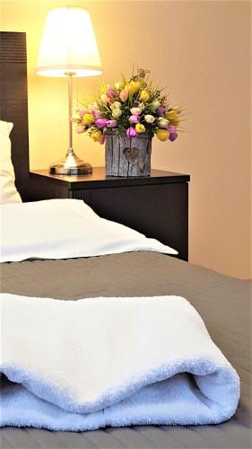 a vase filled with flowers sitting on a bed at SCSK Żurawia in Warsaw