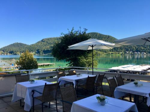 a restaurant with tables and chairs with a view of a lake at Appartement Hotel Marolt in Sankt Kanzian