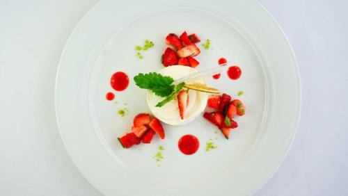 a white plate with strawberries and cream on it at Le Mont-Vully - Hôtel Restaurant in Haut-Vully