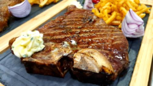 a piece of meat with sauce and french fries at Hotel Escalade in Poiana Brasov