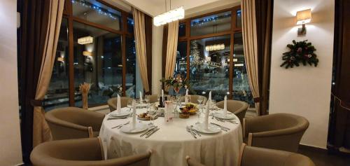a dining room with a white table and chairs at Hotel Escalade in Poiana Brasov