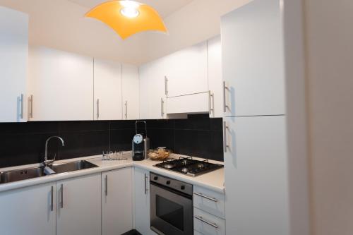 a kitchen with white cabinets and a sink and a refrigerator at Cà Sottomarina gli Appartamenti in Centro Apartsuite in Sottomarina
