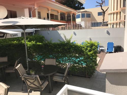 a patio with a table and chairs and an umbrella at Casas de Luanda GH-Miramar in Luanda