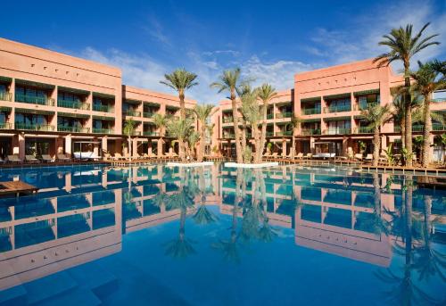 Hôtel Du Golf Rotana Palmeraie في مراكش: منتجع فيه مسبح امام مبنى
