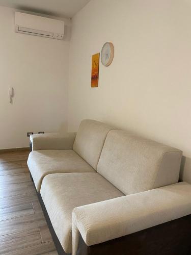 a couch in a living room with a clock on the wall at B&B MaDie in Castelsardo