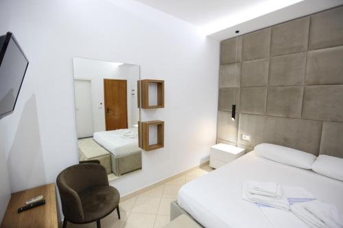 a bedroom with two beds and a chair and a mirror at Ksamil Central Park Hotel in Ksamil