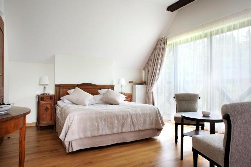 a bedroom with a bed and a table and a chair at Hotel SPA Dr Irena Eris Wzgórza Dylewskie - Siedliska in Wysoka Wieś
