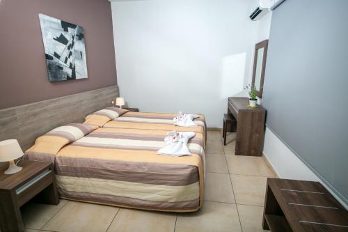 a hotel room with two beds and two tables at Crystallo Apartments in Paphos City