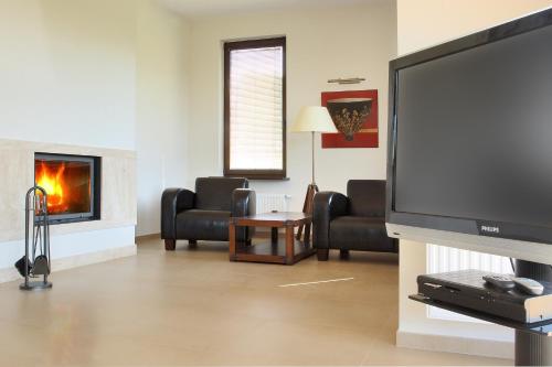 a living room with a flat screen tv and a fireplace at Hotel SPA Dr Irena Eris Wzgórza Dylewskie - Siedliska in Wysoka Wieś