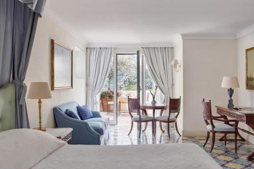a bedroom with a blue couch and a table and chairs at Caruso, A Belmond Hotel, Amalfi Coast in Ravello