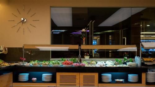 伊斯坦布尔Prestige Hotel Old City的柜台上摆放着几盘食物，墙上挂着一个钟。