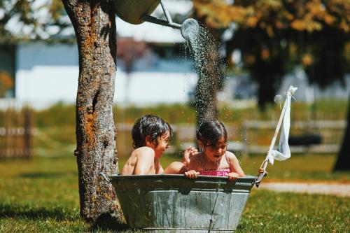 two children playing in a bucket under a tree at Der Stern - Nachhaltiges Wirtshaus und Landhotel seit 1509 in Obsteig