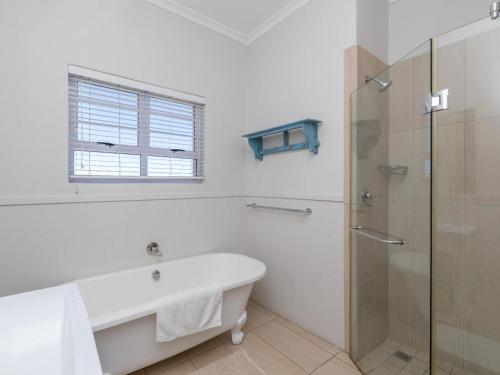 a white bathroom with a tub and a glass shower at Lagoon Escape Beach Villa in Langebaan