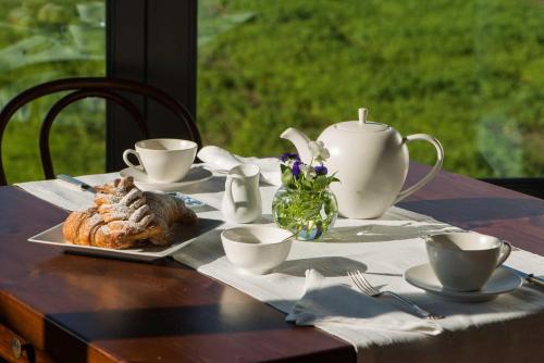 einen Tisch mit einem Teller Essen und Tassen sowie einer Teekanne in der Unterkunft Cascina Canée in Angera