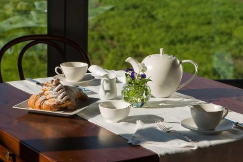 a table with a plate of food and cups and a tea pot at Cascina Canée in Angera
