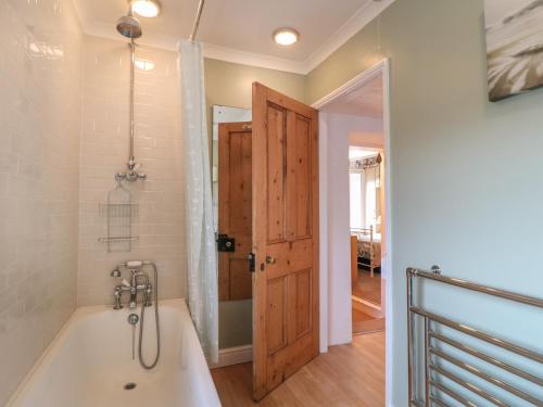 a bathroom with a bath tub and a door at Lavender Cottage in Belper