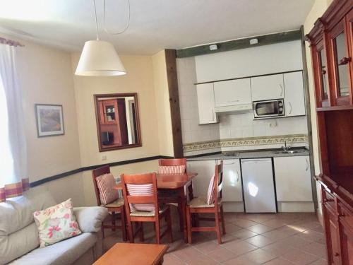 Una sala de estar con un sofá y una mesa y una cocina. en IMEDA Apartamento SALVIA, en Sierra Nevada