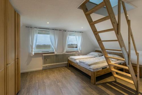 a bedroom with a bunk bed and two windows at Ferienhaus Nordseerobbe in Friedrichskoog
