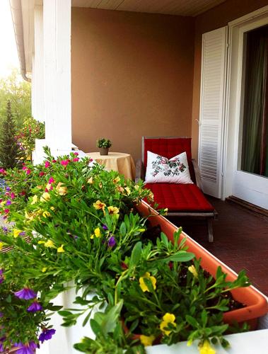 a balcony with flowers and a couch on a porch at Residenz am See in Sankt Kanzian