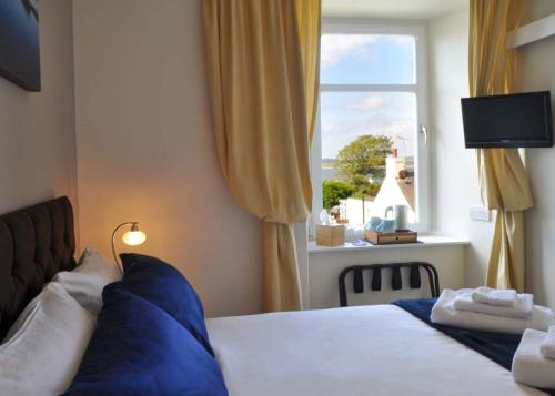 a bedroom with a bed with blue pillows and a window at An Cuan Bed & Breakfast in Bowmore
