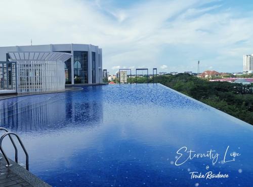 - une piscine d'eau bleue en face d'un bâtiment dans l'établissement Troika Residence Kota Bharu @ Eternity Live-1B4pax, à Kota Bharu