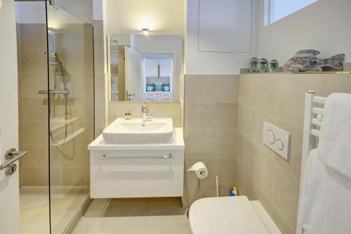 uma casa de banho com um lavatório, um WC e um espelho. em fewo1846 Intermar - Rooftop - Luxuriöses Studioapartment mit Balkon und Meerblick im 7 OG em Glücksburg