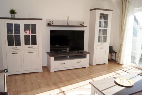 ein Wohnzimmer mit weißen Schränken und einem Flachbild-TV in der Unterkunft Winterberg Appartement 21109 in Winterberg