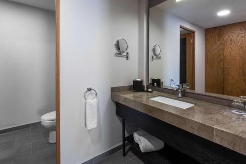 a bathroom with a sink and a mirror and a toilet at TRYP by Wyndham San Luis Potosi Hotel & Suites in San Luis Potosí