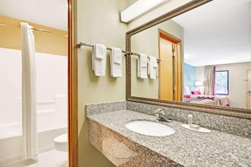 a bathroom with a sink and a mirror at Super 8 by Wyndham Forest Park in Forest Park