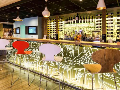 a bar with chairs and a counter with wine bottles at ibis Honfleur in Honfleur
