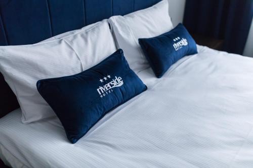 two blue pillows sitting on a white bed at Riverside Hotel in Włocławek