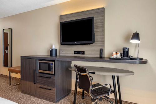 a hotel room with a desk with a tv and a table at Comfort Inn & Suites North Dallas-Addison in Dallas