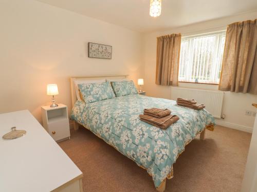 a bedroom with a bed with a blue comforter at Enlli in Holywell